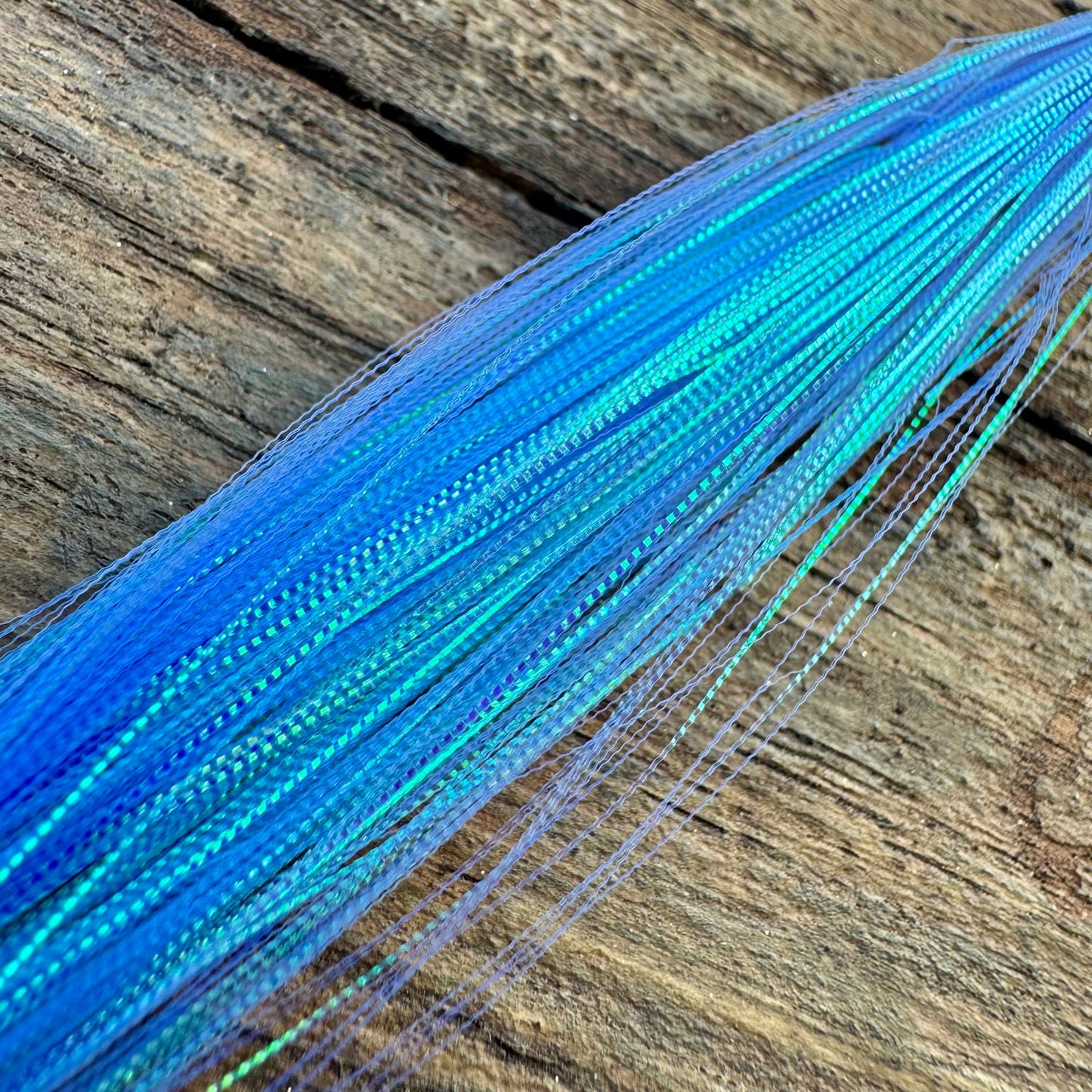 Close-up of Upavon Apex Predator Micro Scale Flash for fly tying, showing shiny, reflective micro scales on a fly fishing materials sheet.